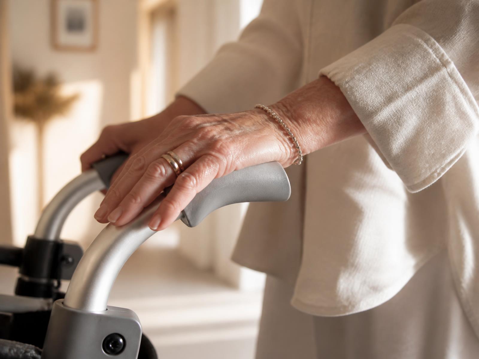 Detalle de una mano apoyada en la empuñadura de un rollator